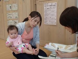 赤ちゃんを膝にのせながら真剣に保健師さんの話を聞いているお母さんの写真