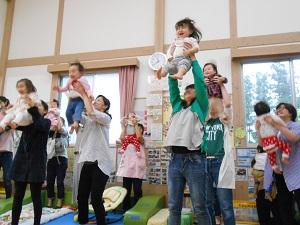 頭の上まで高く子供を抱き上げている母親の写真