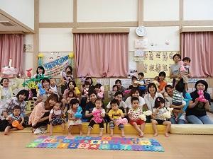 子どもの遊びスペースに参加した親子が座り、それぞれバルーンアートを持っている集合写真