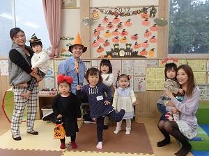 中央に先生と子供たち、両端に子供を抱いた母親が写っている集合写真