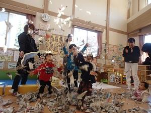 びりびり破いた新聞紙を上に放り投げて喜んでいる子供達とその様子を笑顔で見ているお母さん方の写真