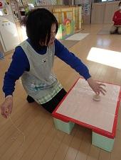 職員の方が机の上でこまを回している写真