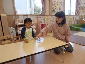 こまの回し方を子供に教えている職員の方の写真