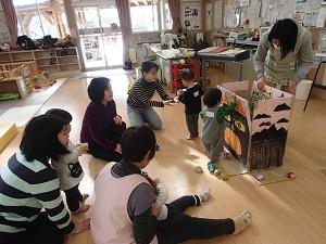 段ボールの片付けを行う職員とそれを見る子供の写真
