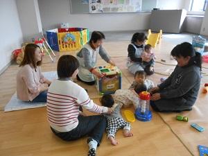 床に座っている女性5名と、赤ちゃん4人四つん這いになったり、女性の膝の上に座っている写真