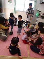 抱っこ紐でおんぶされている赤ちゃん、保育ボランティアさんに抱っこされている泣いている赤ちゃん、保育ボランティアさんと一緒におもちゃで遊んでいる女の子、好きなおもちゃで遊んでいる男の子が写っている別室保育の様子の写真