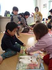男の子と女の子が向い合って座り、仲良く絵本を読んでいる写真