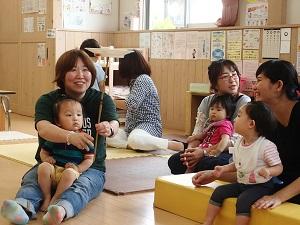 子どもを膝の上に座らせて皿回しをしている母親と傍にいる二組の親子の写真