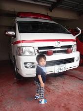 男の子が救急車の前で振り向き記念撮影している写真
