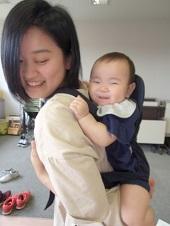 抱っこ紐んで背負われた赤ちゃんと母親が笑顔の写真