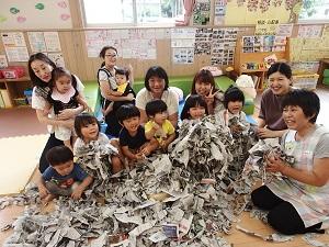 「みんなのお誕生日（令和元年8月）」の参加者が集まって大量の新聞紙の紙片に囲まれている写真