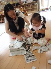 新聞紙を破る子供と保護者の写真