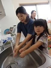 母親と一緒に手を洗う女の子の写真