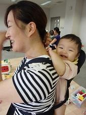 紺色の抱っこ紐で背負われた赤ちゃんと母親の笑顔の写真