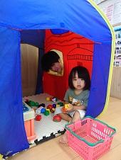 テントの中で遊ぶ女の子とテントの窓から顔を出し覗き込んでいるお父さんの写真