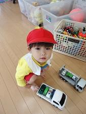 トラックのおもちゃとミニカーで遊んでいる男の子の写真