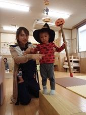 赤ちゃんを抱っこ紐で抱えながら平均台の上を歩く子供を支える保護者の写真