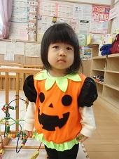オレンジ色のジャックオーランタンの衣装を身につけた子供の写真