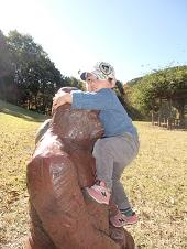 公園に設置されている大きなゴリラの置物の頭に抱きついている女の子の写真
