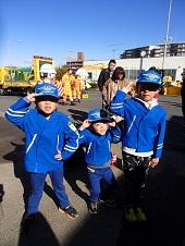 青い帽子と制服を身につけて敬礼ポーズをしている3人の子供の写真