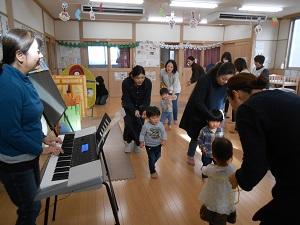 小林先生のピアノに合わせて体を動かす親子たちの写真