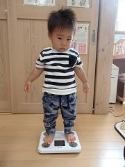 直立で頑張って体重計に立っている男の子の写真