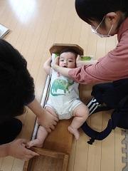 寝転んで身長を計っている赤ちゃんの頭を動かないようにお母さんがおさえ測定をしている写真