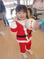 サンタの格好をした女の子ががボールを持って笑顔でポーズをとっている写真