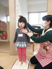 直立でまっすぐ前をみている女の子の顎を保健師さんが触りながら身長を計っている写真
