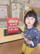 箱と紙でできた雛人形の前に立っている女の子の写真