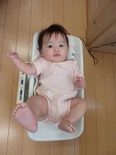 肌着姿で体重計に寝ころび測定してもらっている赤ちゃんを真上から写した写真