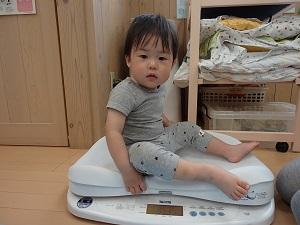 体重計に座り横を向いている男の子の写真