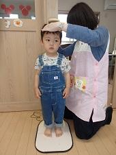 ジーンズ姿の男の子の頭に保健師さんが手をあて身長を測っている写真
