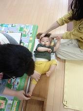 お母さんが赤ちゃんの頭を押さえ赤ちゃんの片足を伸ばして身長測定をしている保健師さんの上から写した写真
