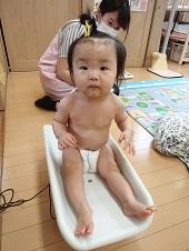 体重計に座っている赤ちゃんと、その後ろに座っている保健師の写真
