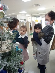 公民館内のクリスマスツリーを抱っこされながら見つめる子どもたち