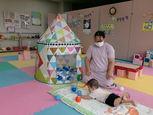 ボールで遊ぶ乳児と見守る母