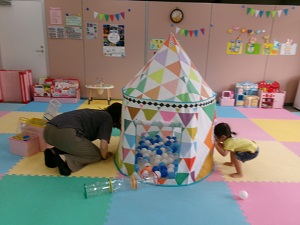 ボールプールのテント越しに顔を合わせる親子