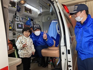 救急車に乗り写真を撮る幼児と消防士さん