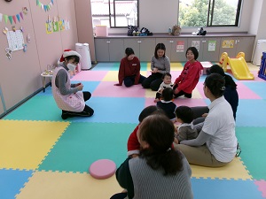 先生と一緒に手遊びをする親子たち