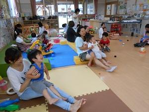 子どもを膝の上に座らせて、講座に参加している沢山の親子がくつろいで座っている様子の写真