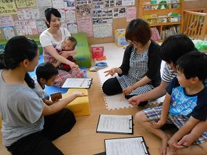 バインダーに挟んだレジュメに目を通しながら、参加者親子がグループで話し合いをしている様子の写真