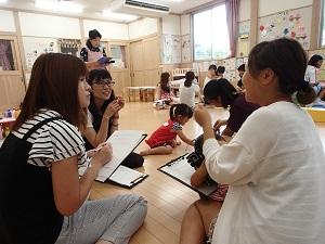 レジュメを挟んだバインダーを手に持って、お母さん方が楽しそうに意見交換をしているグループワークの様子の写真