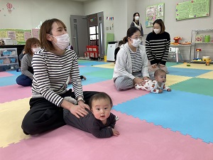 うつぶせの赤ちゃんをマッサージする母たち