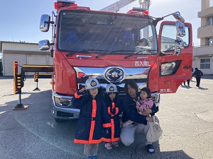 はしご車の前で記念写真を撮ってもらう父と子どもたち