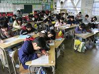 教室で2つの机をつけて座っている児童たちが、用紙に向かって記入している様子の写真