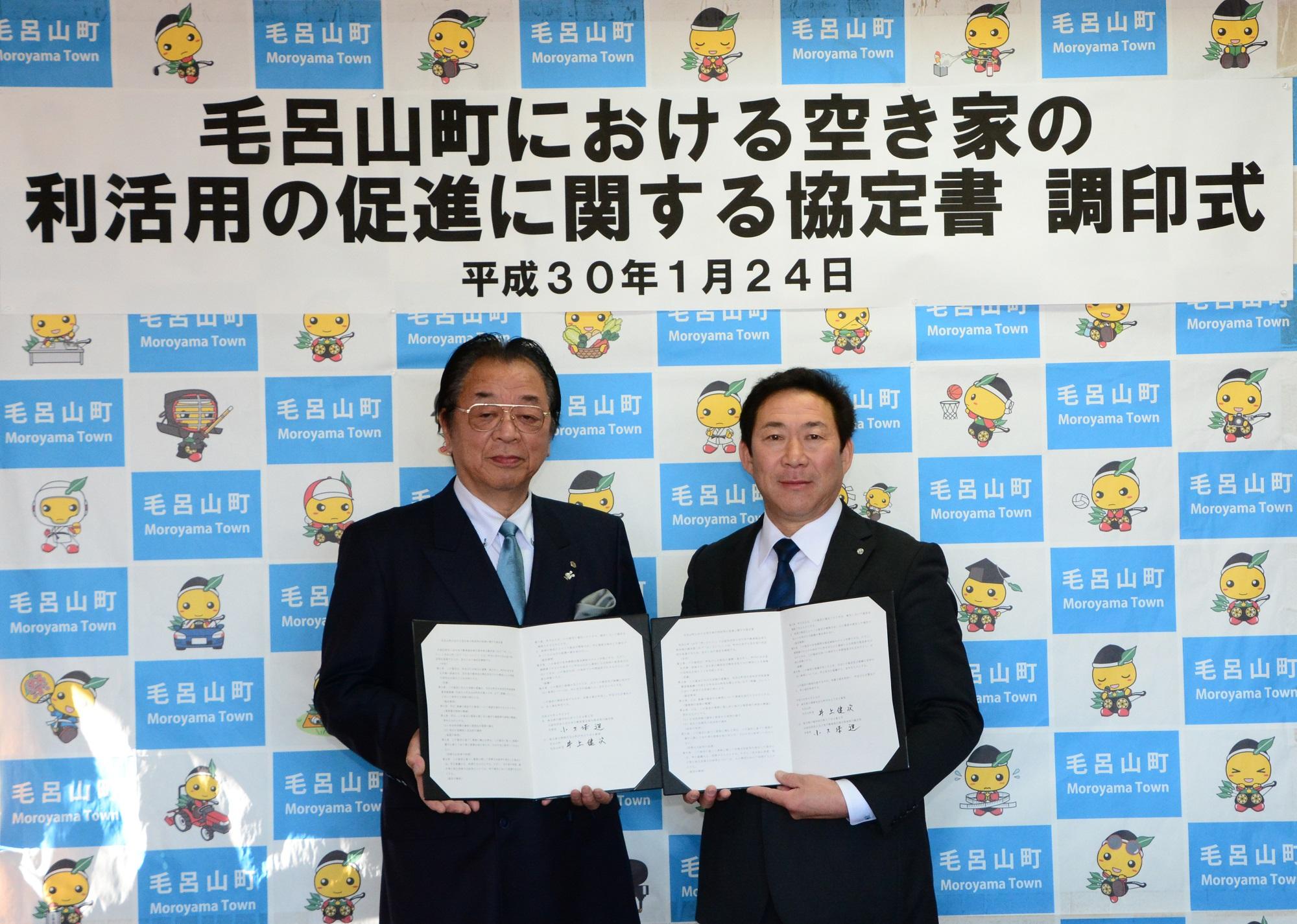 全日本不動産協会川越支部の方と町長が協定書をそれぞれ開いて持ち、並んで記念撮影をしている写真
