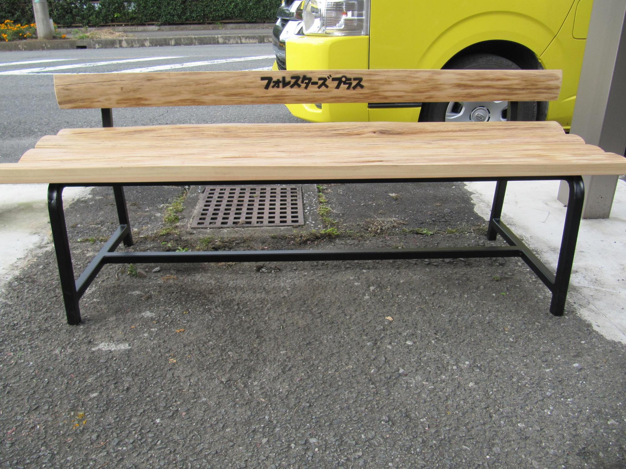 木製のベンチの背もたれに「フォレスターズプラス」と文字の入ったベンチの写真